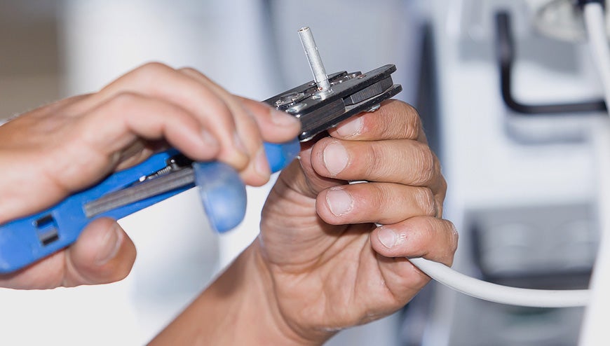 Electrician using wire crimping tool during a residential cable repair.