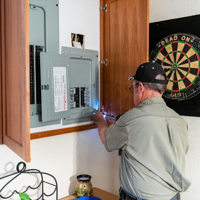 Electrician inspecting and adjusting breakers in a residential breaker panel.