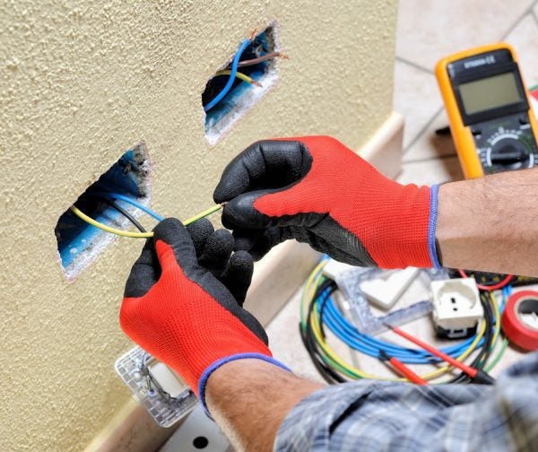 Electrician installing wires into wall outlets during rewiring work